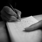 Photo of a person writing in a notebook.